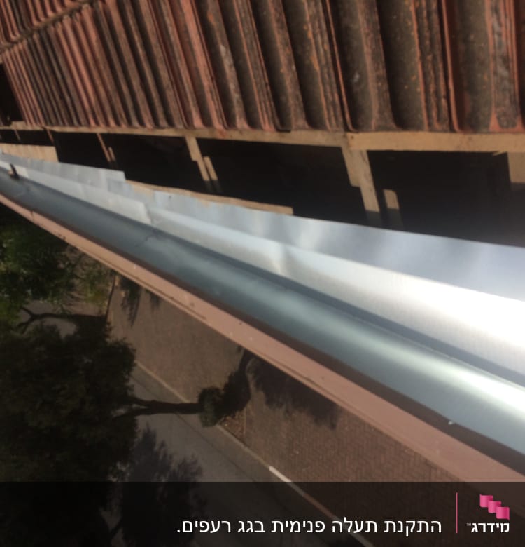 מרזב מתכת מותקן על גג רעפים